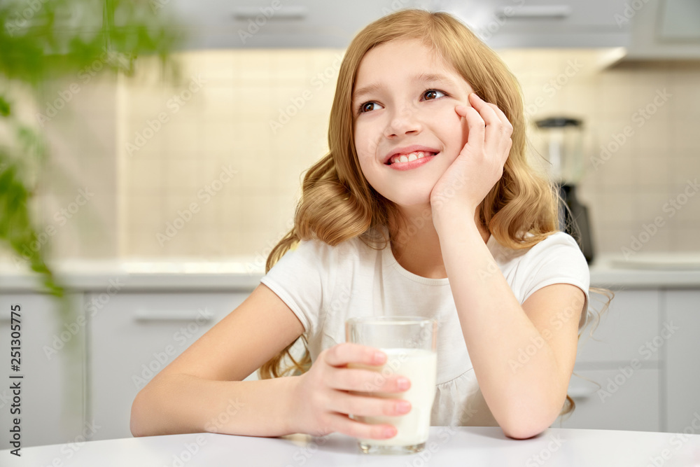 Happy girl sitting in kitchen, holding milk glass. Happy girl sitting in kitchen, holding milk glass.