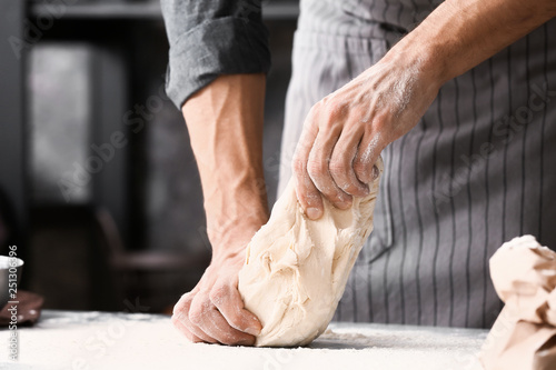 Young man preparing dough for bread in kitchen