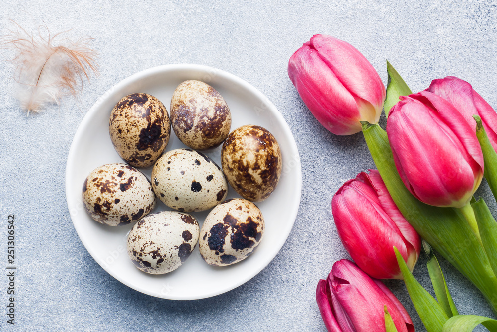 Bright flowers tulips and quail eggs on stone background. Spring and Easter holiday concept with copy space