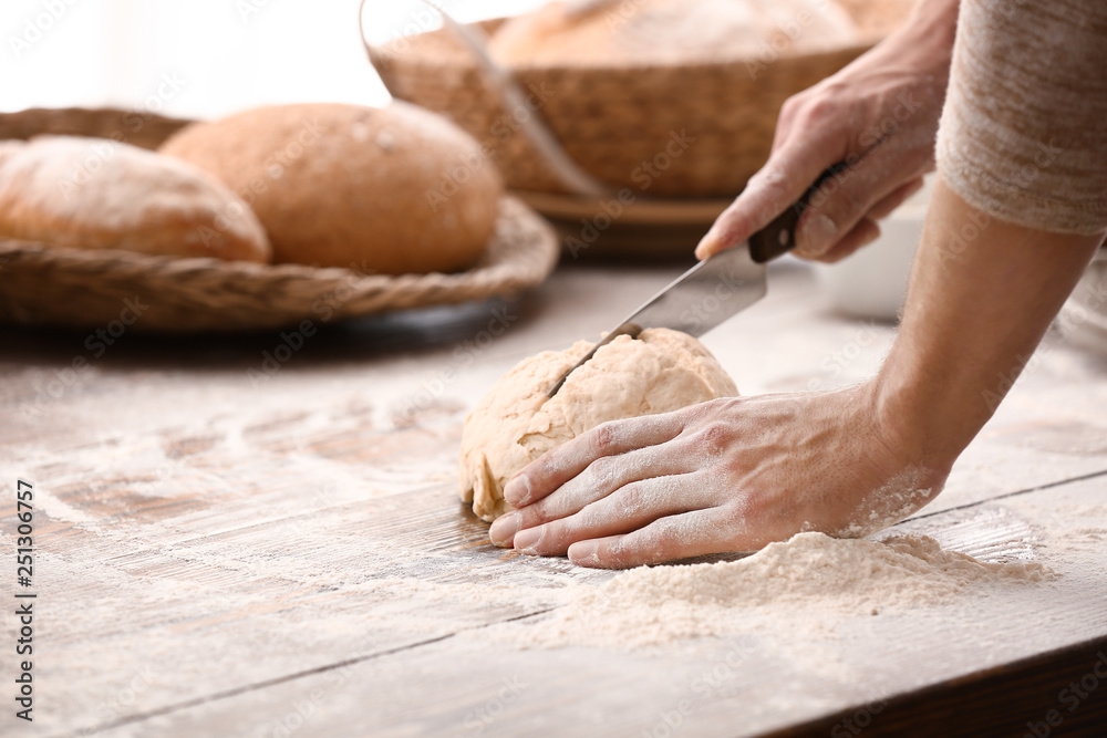 Young man preparing dough for bread in kitchen, closeup
