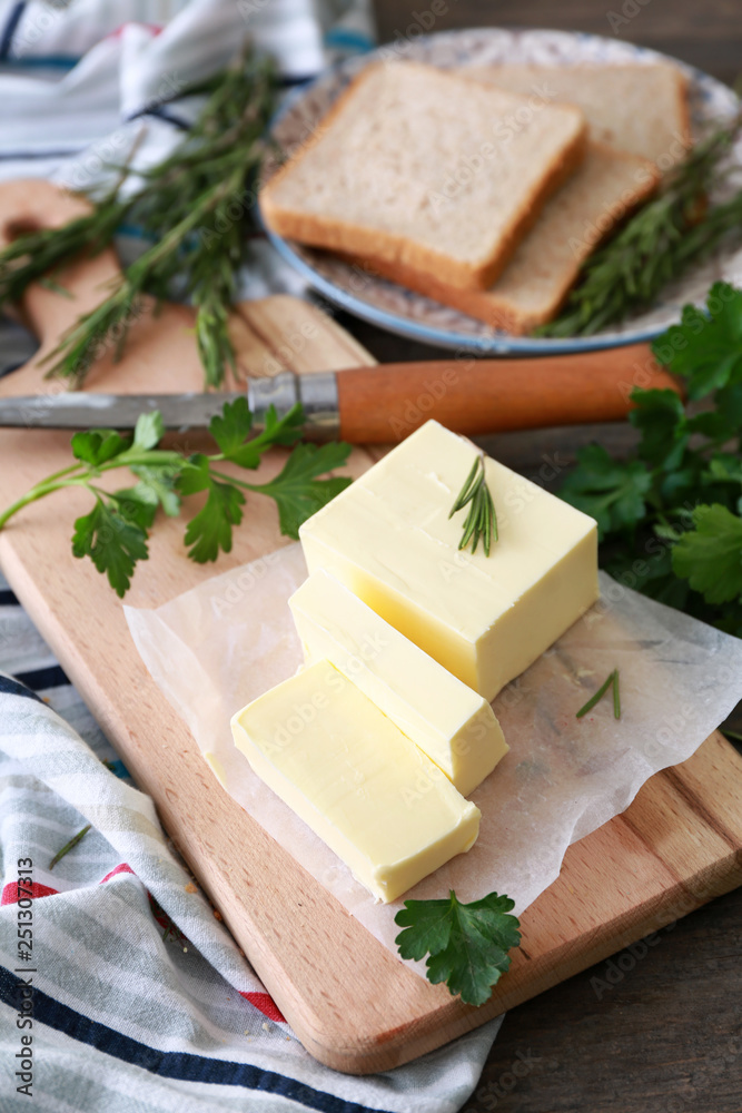 Wooden board with tasty butter and herbs on table