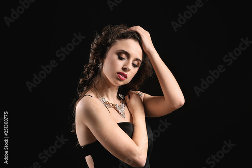Young woman with beautiful jewelry on dark background