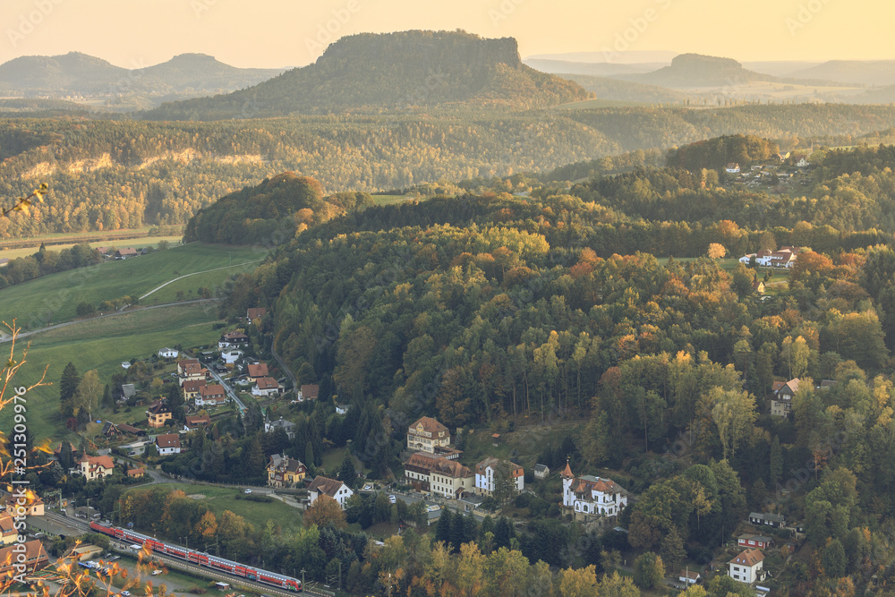 View into the valley of the Bastei bridge in the national park Saxon Switzerland in the Elbe Sandstone Mountains. Place Neurathen with train on sunny evening in autumn and mountain formation