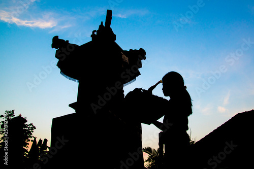Silhouette of a hinduism woman who is praying at the temple of Bali