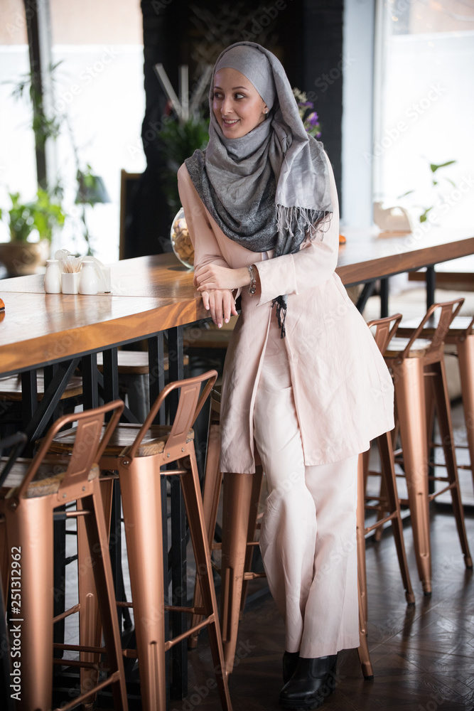 A young muslim woman sitting on a bar chair in a restaurant