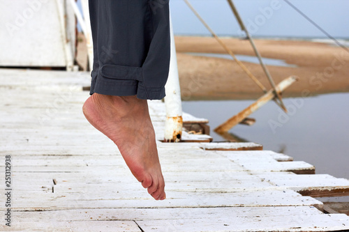 Valokuva Legs of a woman hovering in the air over a white wooden pier