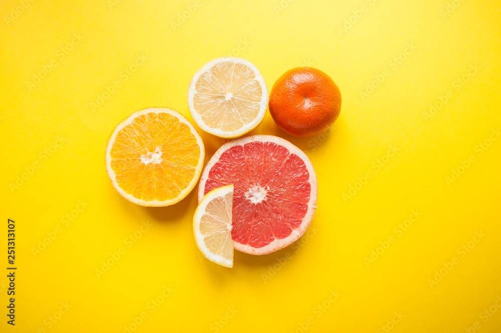 Flat lay of cut ripe juicy grapefruit, lemon and orange on yellow background. Citrus pattern. Flat lay of cut ripe juicy grapefruit, lemon and orange on yellow background. Citrus pattern.