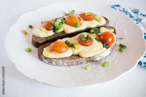 Multigrain toast bread with melt gouda or kaseri cheese and small tomatoes and green onion on top 