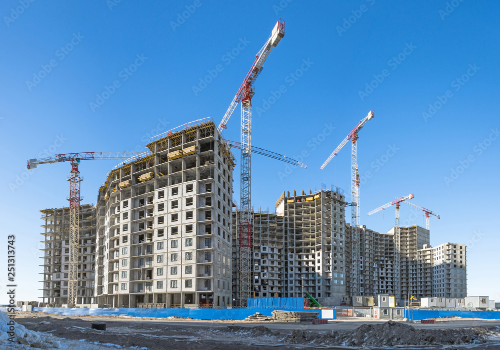 Panoramic view of a construction site with high cranes of apartment houses in microdistricts