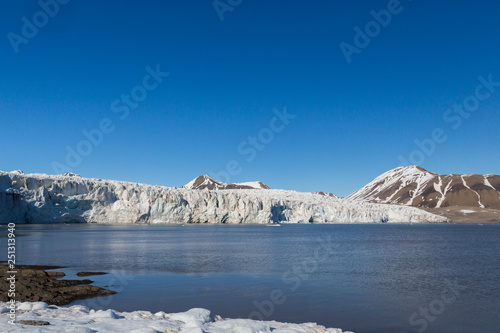 ice front of Esmarkbreen glacier in summer, Spitsbergen, blue sky, sea