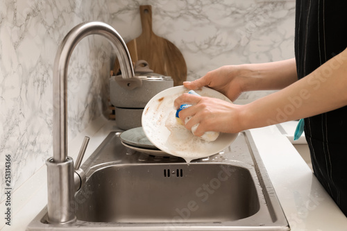 Obraz na plátně Woman washing dishes in kitchen sink