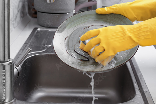 Fotografie Woman washing dishes in kitchen sink