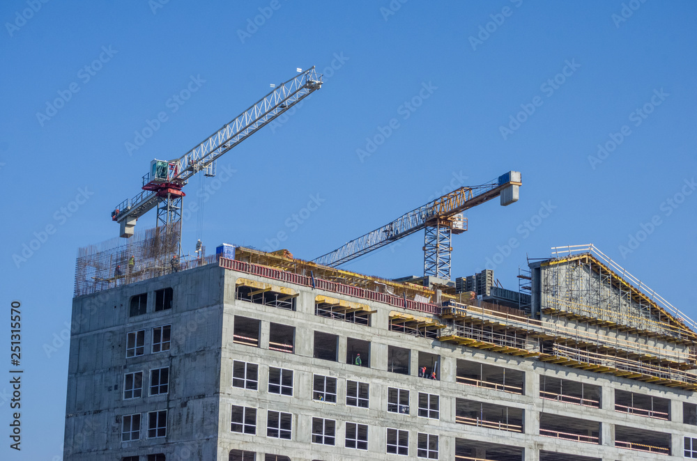 Building crane and building under construction against blue sky