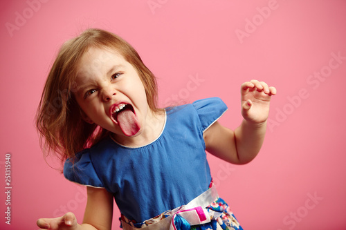 Angry little girl shows her tongue in funny grimace