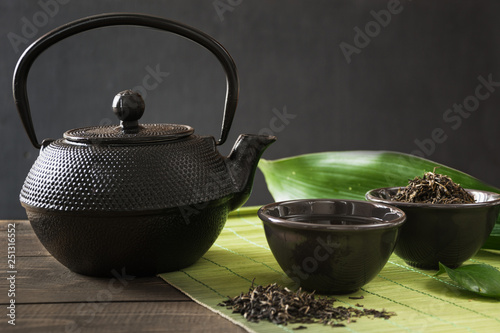 Cup with green tea with black china kettle on black with copy space. Close up. Chinese tea concept.