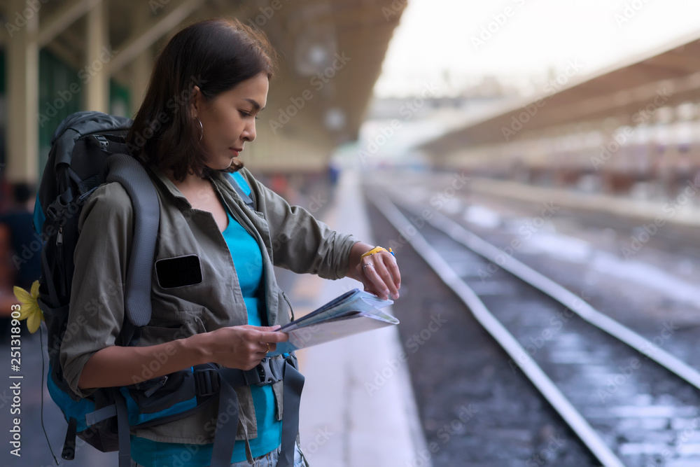 Obraz premium Asia woman stand wait train for traveler trip and checking time on her watch.