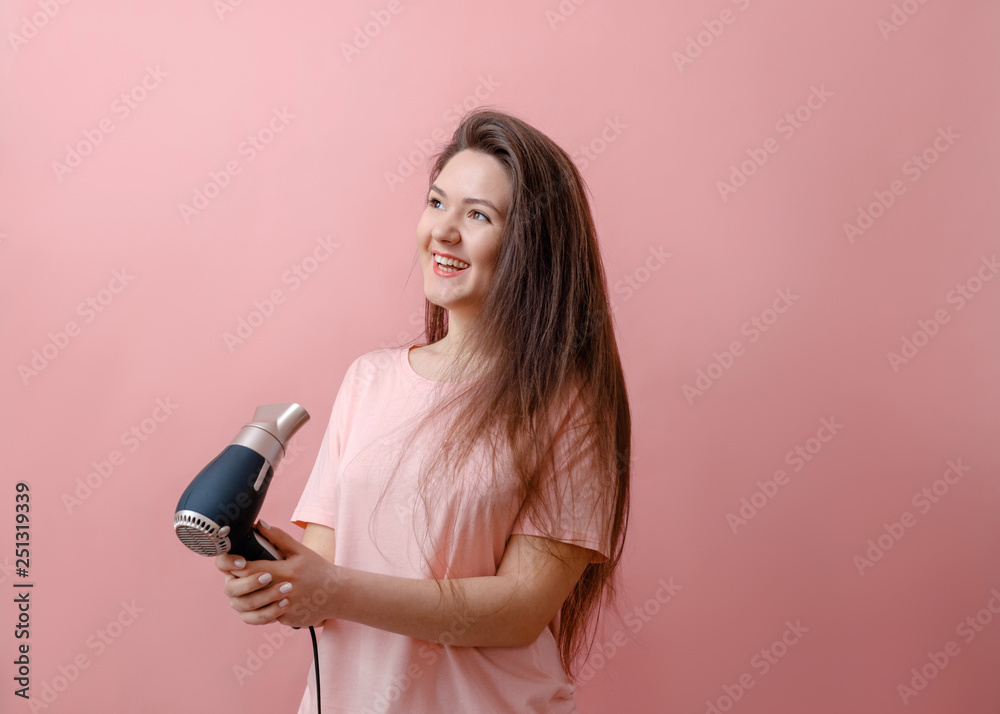 young smiling woman with hairdryer in hands on pink background young smiling woman with hairdryer in hands on pink background