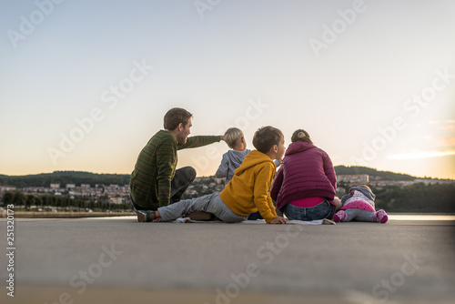 Family of five sitting on wooden pier