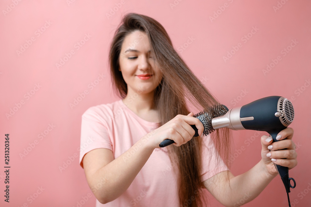 young smiling woman with hairdryer in hands on pink background young smiling woman with hairdryer in hands on pink background