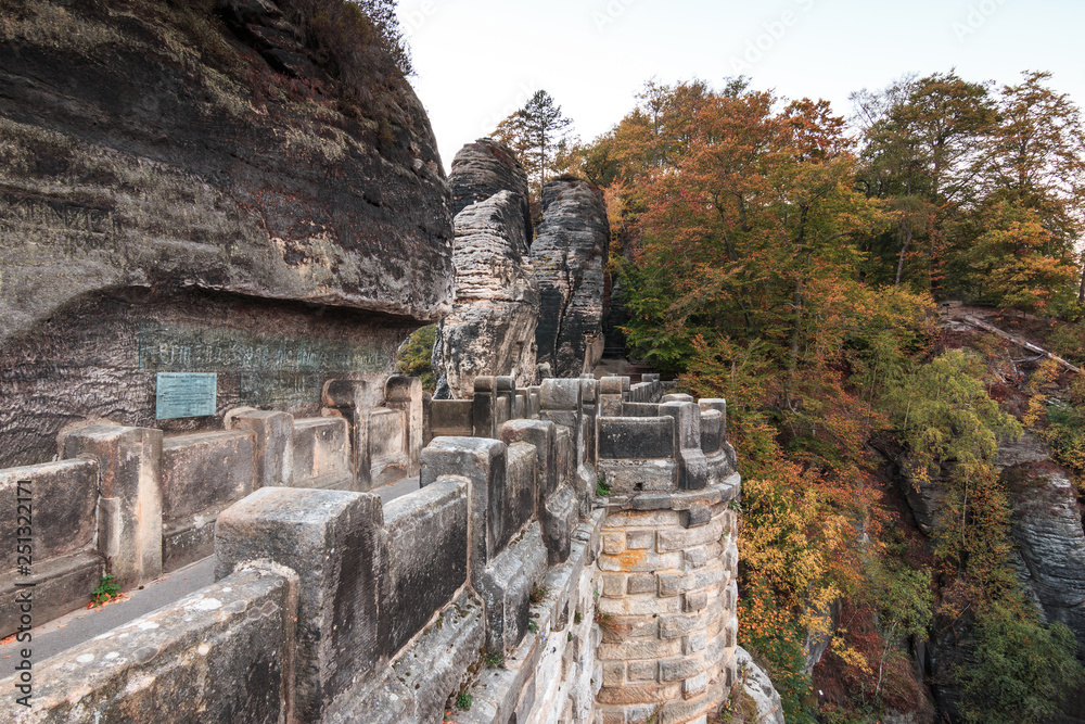 Bastei bridge in the national park Saxon Switzerland. Elbe sandstone mountains. lateral panoramic view on historical brickwork of fortress with rock formations and trees in autumn.