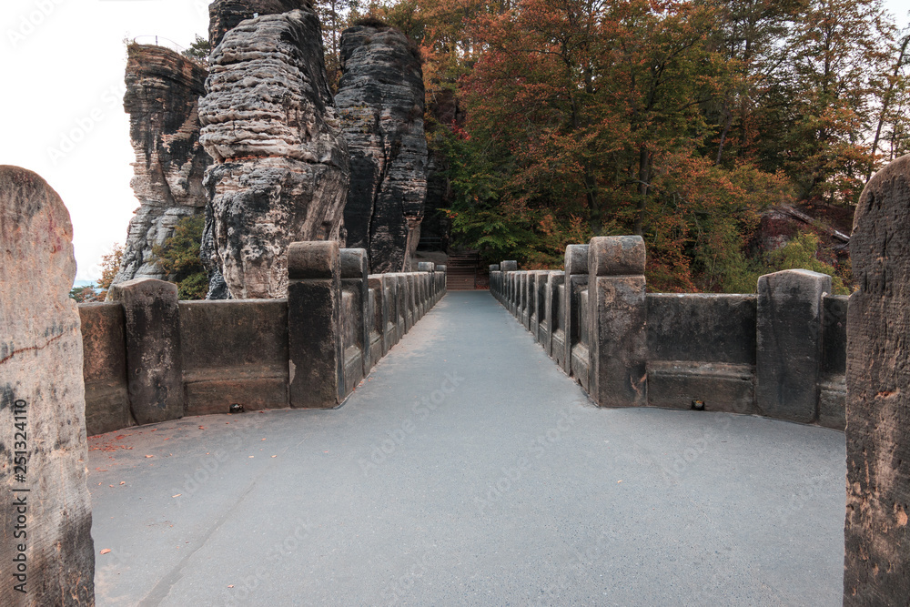 Upper course and footpath above the Bastei bridge in the Saxon Switzerland National Park Elbe Sandstone Mountains. Fortress and historic stonework with rock formations and trees in autumn. Upper course and footpath above the Bastei bridge in the Saxon Switzerland National Park Elbe Sandstone Mountains. Fortress and historic stonework with rock formations and trees in autumn.