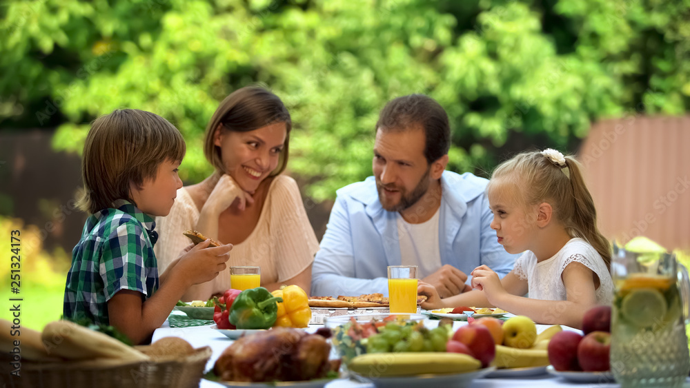Friendly family having traditional dinner outdoors, parents kids happy together