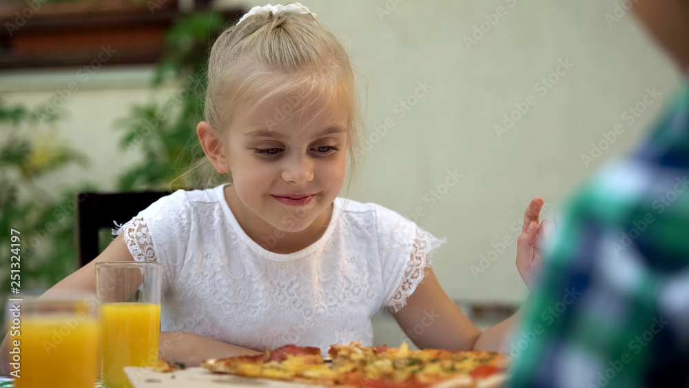 Smiling girl looking with love at tasty pizza in outdoor restaurant, appetite