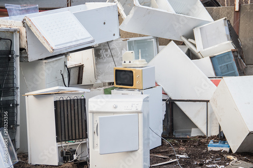 A stack of old white electrical household appliances waste such as a fridge or microwave, ecologically disposed of in a landfill (dump, collection yard). of hazardous waste.