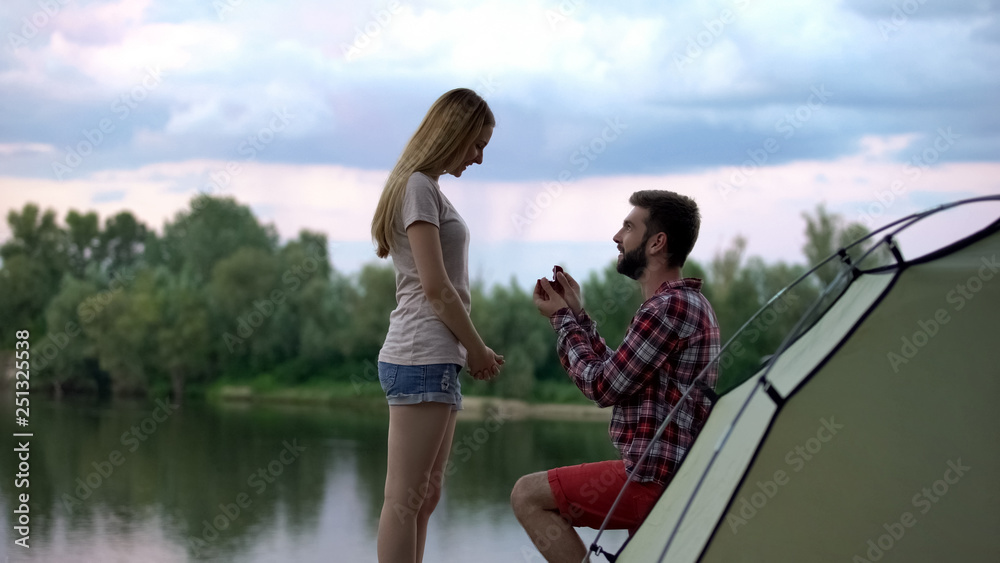 Young man proposing to girlfriend at forest, romantic engagement, happiness