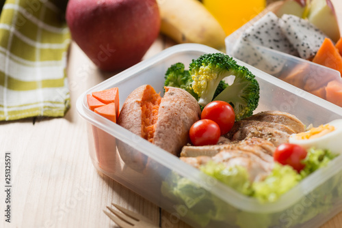 Healthy lunch boxes in plastic package, Grilled chicken breast with sweet potato, egg and vegetable salad, fruit, orange juice. Diet food concept.