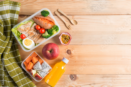 Healthy lunch boxes in plastic package, Grilled chicken breast with sweet potato, egg and vegetable salad, fruit, orange juice. Diet food concept. Top view and Copy space.