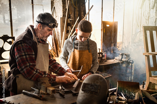 A craftsman in his workshop teaches his work to his apprentice photo
