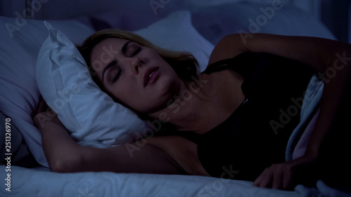 Canvas Print Beautiful female sleeping on bed at night, resting after hard working day, snore