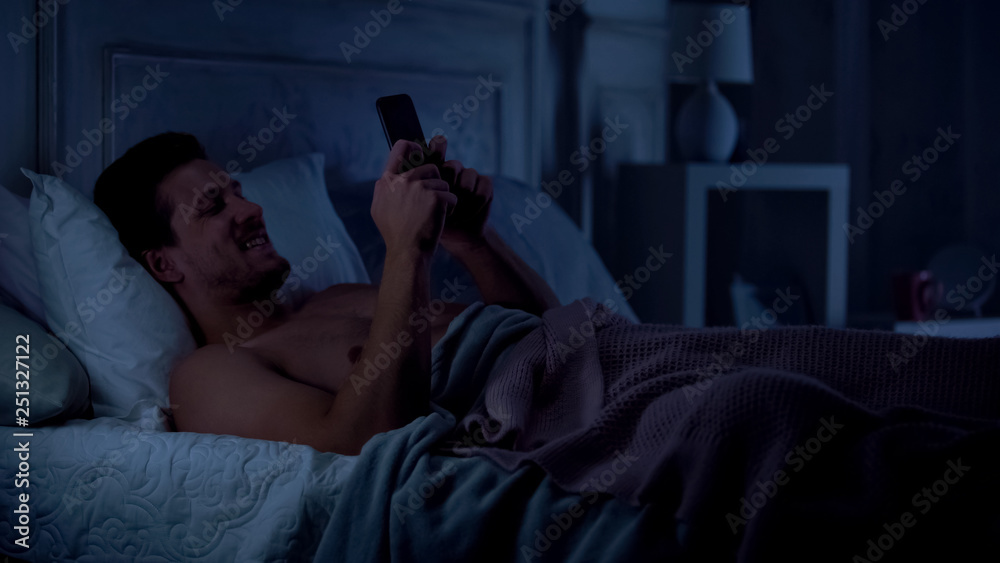 Fototapeta premium Young male texting on smartphone and smiling, chatting with girlfriend, gadget