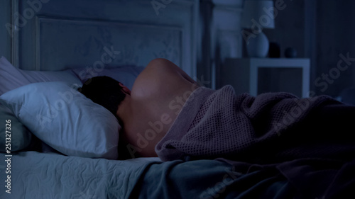 Obraz na płótnie Man lying in bed, incorrect sleeping position for neck and spine, unhealthy