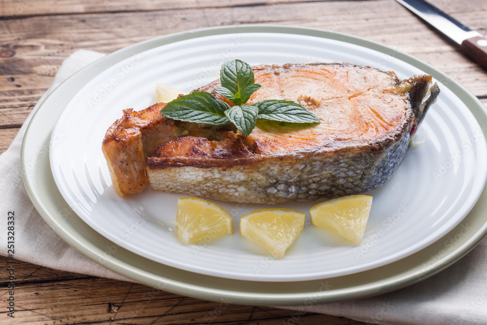 Steak baked fish salmon on a plate with lemon. Wooden table. Steak baked fish salmon on a plate with lemon. Wooden table.