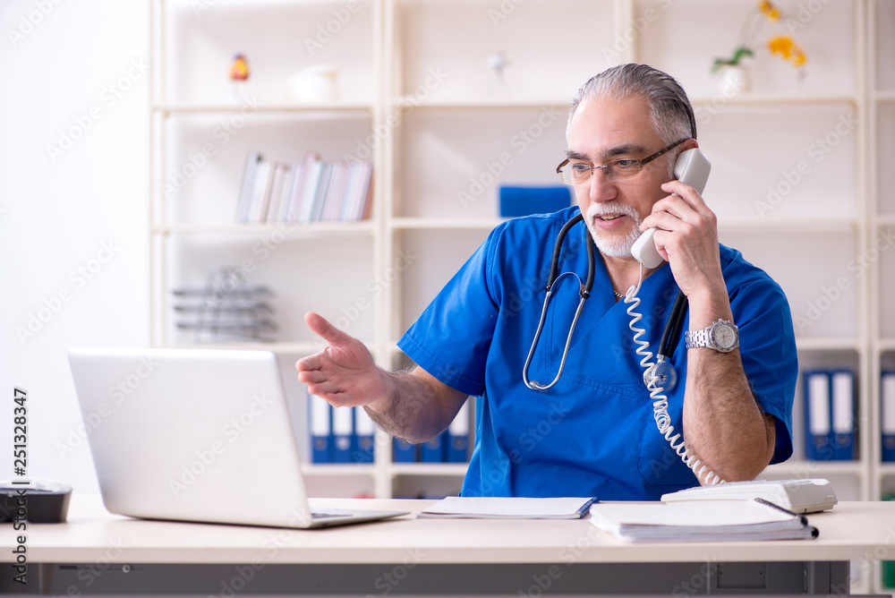 White bearded old doctor working in clinic White bearded old doctor working in clinic