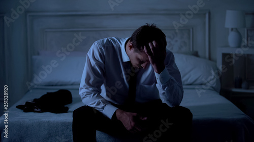 Sad lawyer sitting on bed at night, failed case, disappointment and frustration © motortion