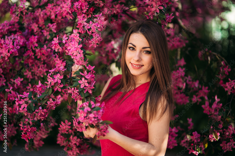 Beautiful lady stand by the big blooming tree voilet color. Happy girl with makeup in spring Beautiful lady stand by the big blooming tree voilet color. Happy girl with makeup in spring