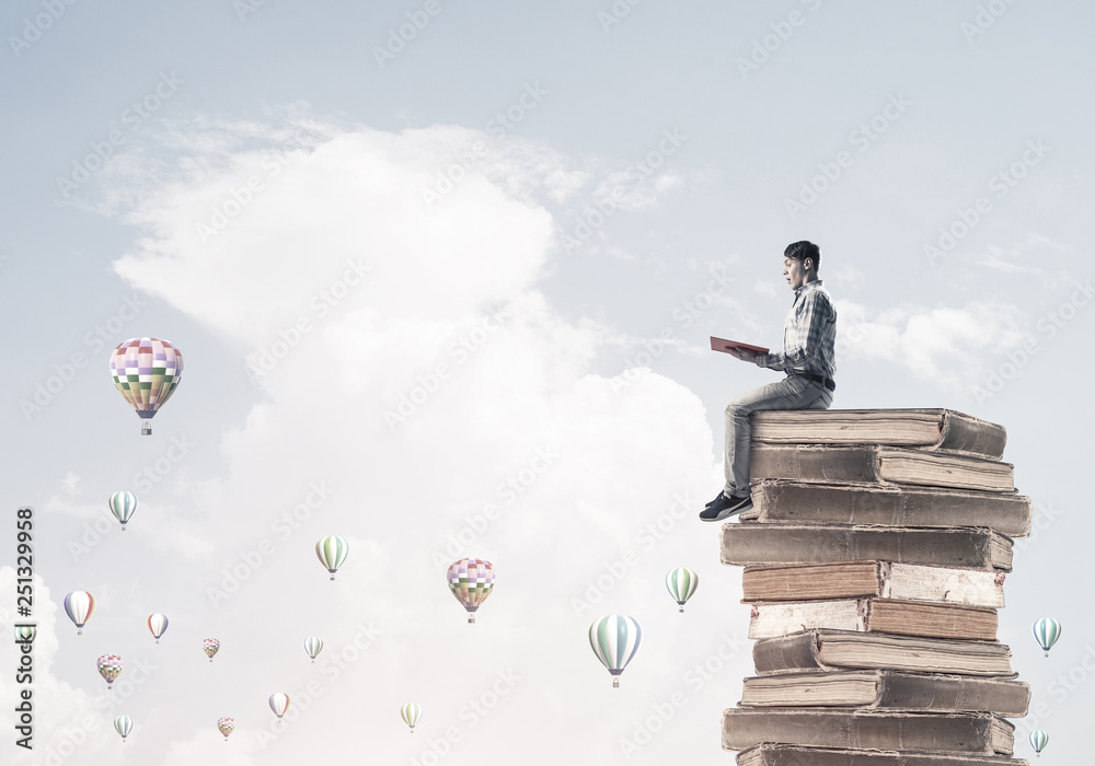 Man student on stack reading book and aerostats flying around Man student on stack reading book and aerostats flying around