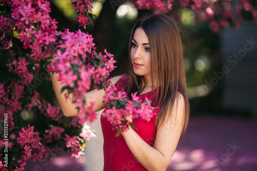 Beautiful lady stand by the big blooming tree voilet color. Happy girl with makeup in spring