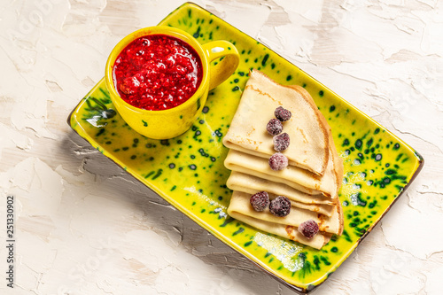 Homemade crepes served with fresh Raspberry and jam on rustic table crepes on yellow plate photo