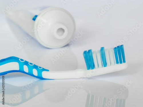 Blue toothbrush on a white glossy background. The concept of daily dental care, oral hygiene, prevention of diseases of the teeth and gums, health care.
