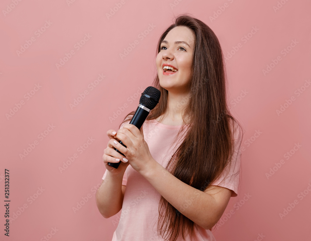 young funny woman with microphone in hand on pink background young funny woman with microphone in hand on pink background