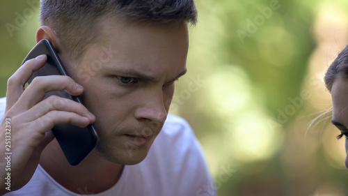 Worried young man calling 911 to report crime or ask for medical help, closeup