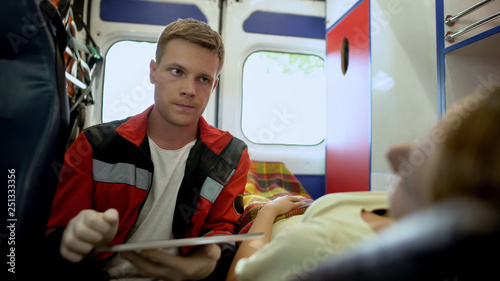 Paramedic asking patient questions and filling out medical form in ambulance