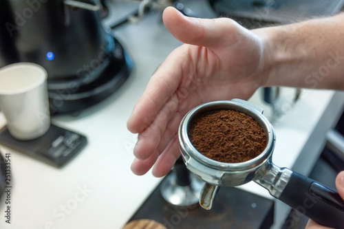 Barista presses ground coffee in the spoon