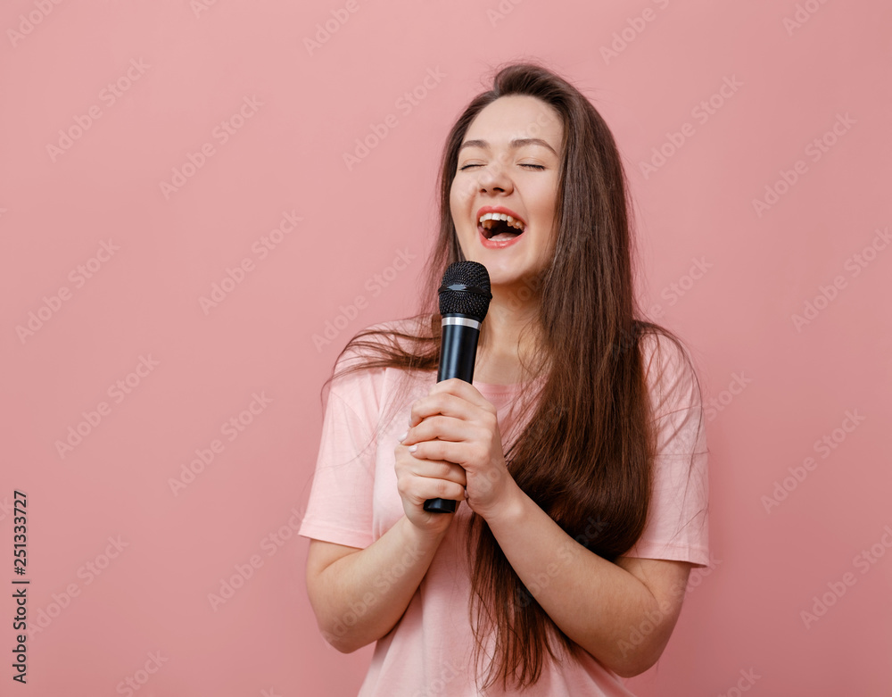 young funny woman with microphone in hand on pink background young funny woman with microphone in hand on pink background