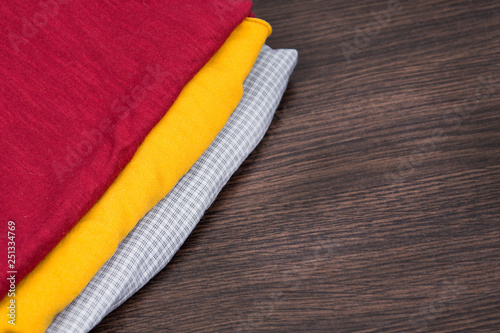 Yellow and red fabric. a stack of clothes  and textiles. Samples of color fabric in the store. Gray checkered fabric. Warm sweaters. Piled things close up.