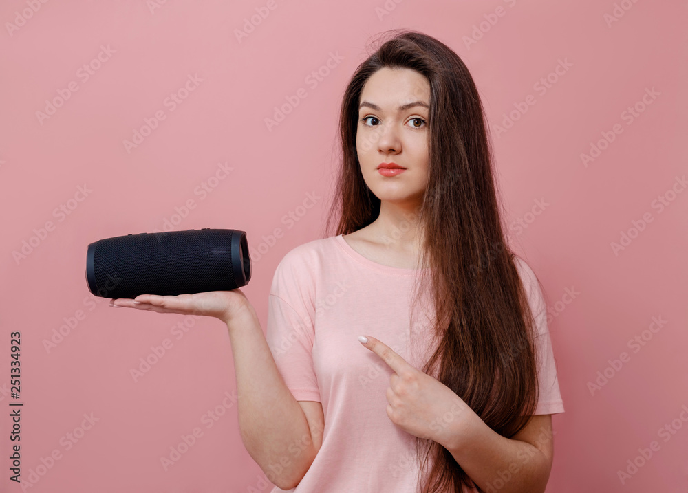 young woman with a portable loudspeaker in hand on pink background young woman with a portable loudspeaker in hand on pink background